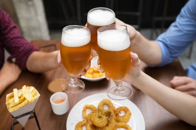 Vista recortada de amigos copas de cerveza tintineo