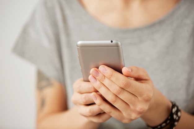 Vista recortada de las manos de una mujer sosteniendo el teléfono móvil