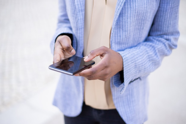 Vista recortada de mensajes de mujer en el teléfono inteligente