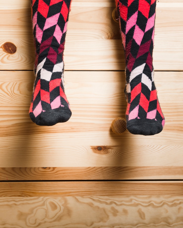 Foto gratuito vista de sección baja de los pies de una niña con calcetines multicolores