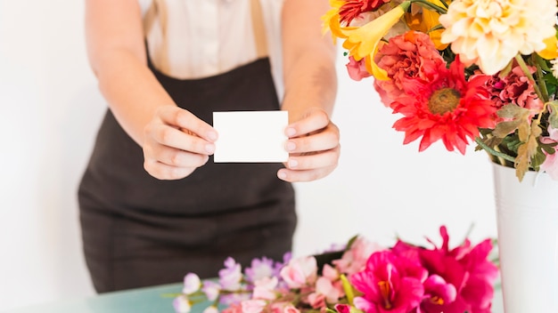 Vista de la sección media de una floristería femenina con tarjeta de visita blanca en blanco