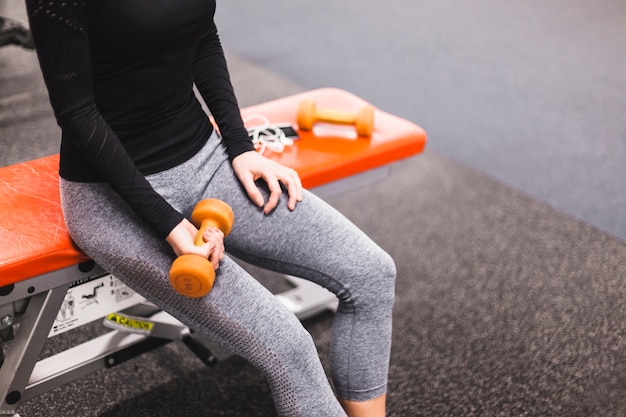 Vista de la sección media de la mano de una mujer haciendo ejercicios con pesas en el gimnasio