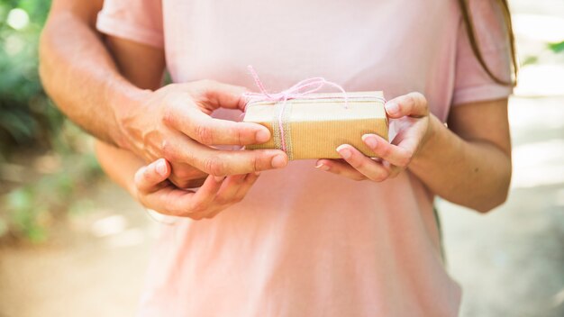 Vista de la sección media de la mano de una pareja sosteniendo la pequeña caja de regalo de San Valentín