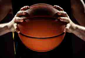 Foto gratuita vista de la silueta de un jugador de baloncesto con baloncesto en la pared negra