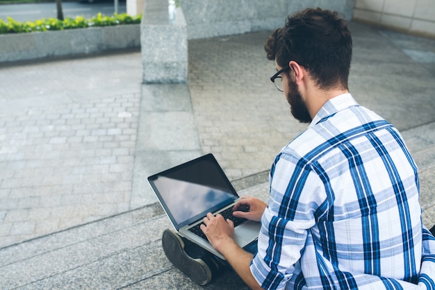 Vista sobre el hombro del hombre codificando en la computadora portátil