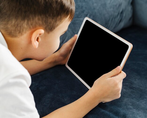 Vista sobre el hombro niño sosteniendo tableta digital