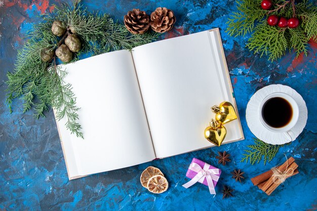 Vista superior abrió cuaderno ramas de abeto conos juguetes de árbol de navidad sobre fondo azul lugar libre
