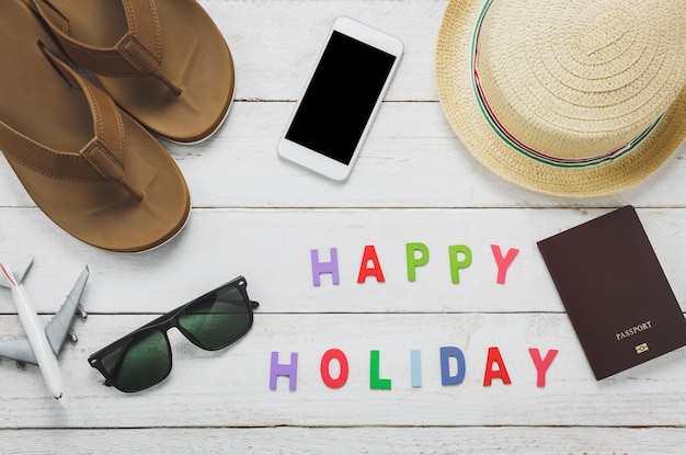 Vista superior de los accesorios esenciales para viajes. Los artículos de viaje concepto con la palabra &quot;HAPPY HOLIDAY&quot;