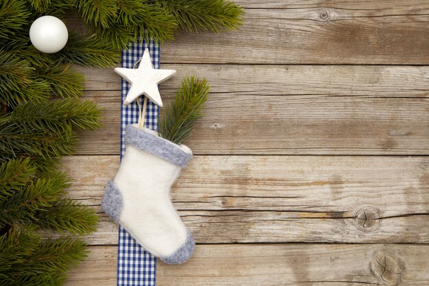 Vista superior de adornos navideños y un calcetín en una mesa de madera con ramas de árboles