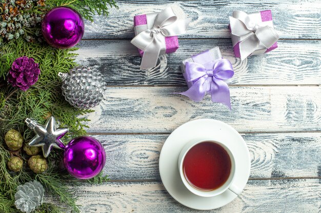 Vista superior adornos navideños una taza de té pequeños regalos ramas de abeto juguetes navideños sobre superficie de madera