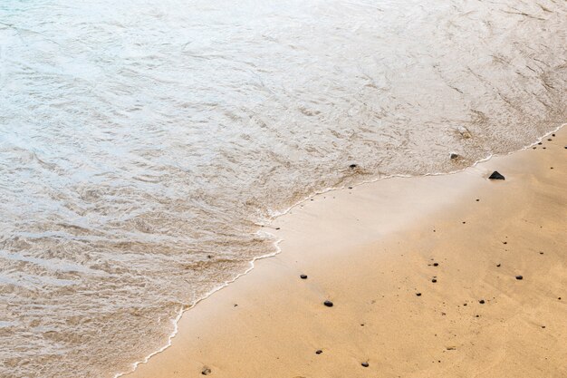 Vista superior de agua de mar tocando arena en la orilla