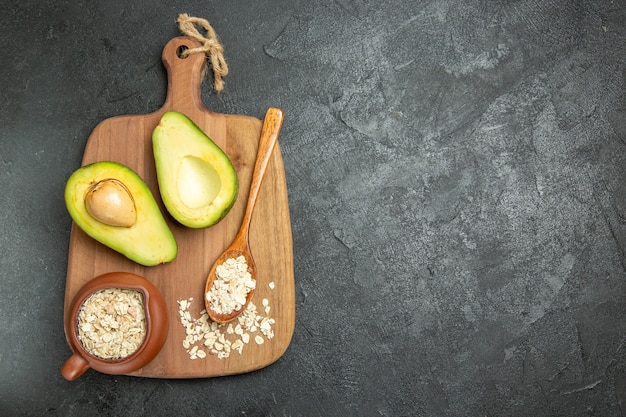 Vista superior de aguacate fresco con cereales crudos sobre el fondo gris desayuno exótico de frutas frescas