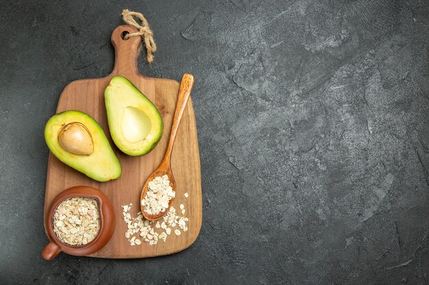 Vista superior de aguacate fresco con cereales crudos sobre el fondo gris desayuno exótico de frutas frescas