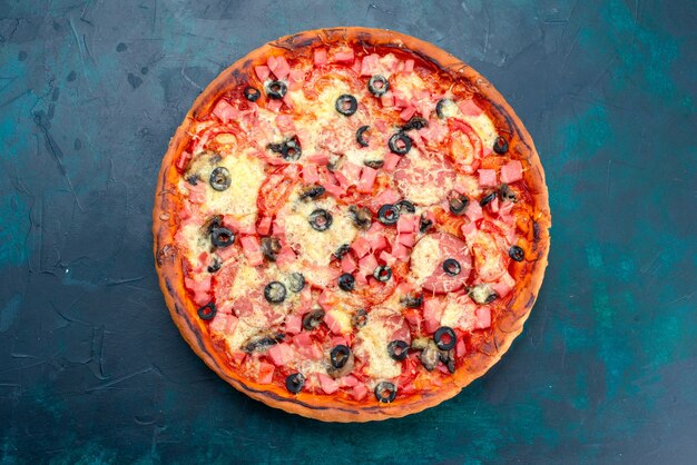 Vista superior al horno deliciosa pizza con aceitunas, salchichas y queso sobre fondo azul.