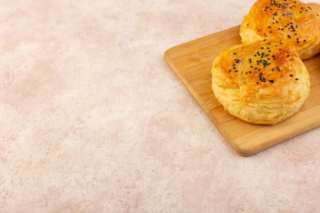 Una vista superior al horno qogals pastelería en forma redonda sabroso caliente recién salido del horno en el escritorio de madera marrón