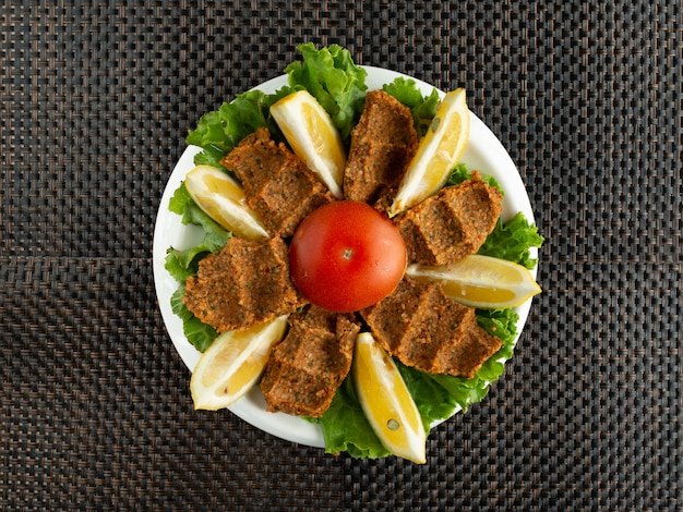 Foto gratuita vista superior de albóndigas crudas de cig kofte turco servidas con lechuga y limón