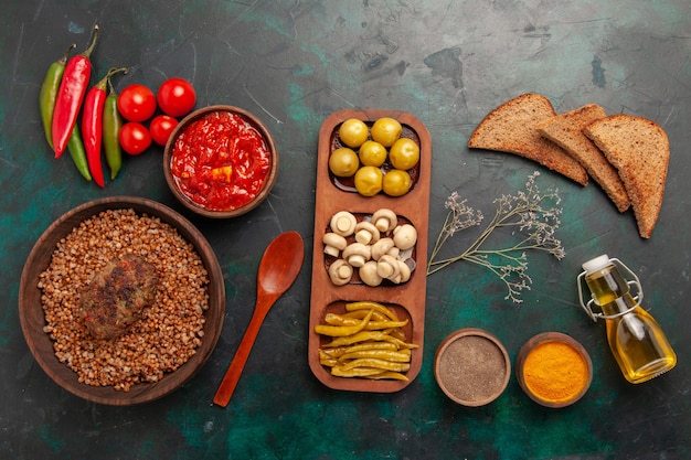 Foto gratuita vista superior de alforfón cocido con chuleta y salsa de tomate en el escritorio verde