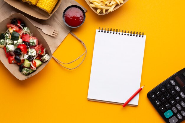 Vista superior de alimentos con el cuaderno sobre fondo amarillo