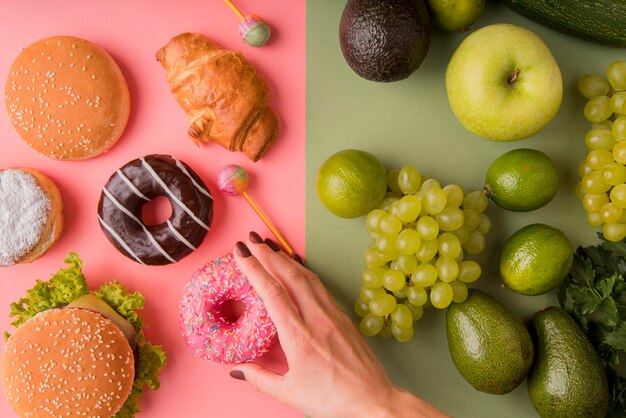 Vista superior de alimentos poco saludables versus alimentos saludables con donut de mano