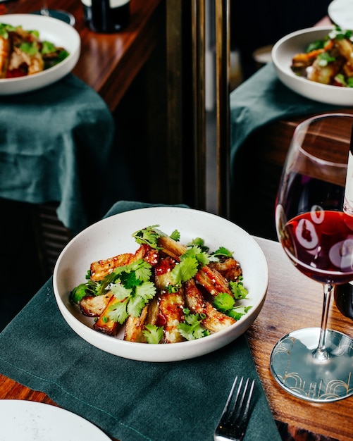 Una vista superior de alitas de pollo en rodajas con ensalada de verduras y vino tinto en la mesa, comida, cena, restaurante