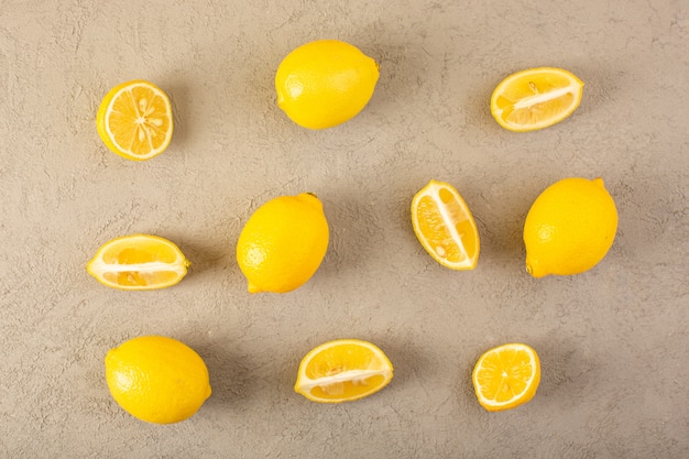 Una vista superior amarillo limones frescos maduros suaves y jugosos enteros y en rodajas forradas en el fondo gris frutas color cítrico