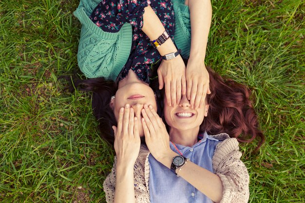 Vista superior de amigos sonrientes tumbado en la hierba divirtiéndose