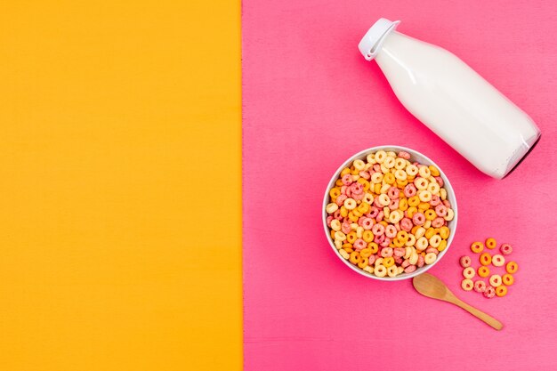 Vista superior de anillos de maíz y leche con copia espacio sobre fondo rosa y amarillo horizontal