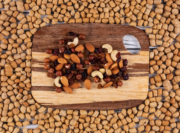 Vista superior de aperitivos como nueces, frutos secos en la tabla de cortar en galletas de textura horizontal