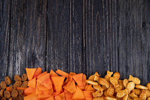 Foto gratuita vista superior aperitivos paprika chips chuck duro y galletas de pescado en la parte inferior con espacio de copia sobre fondo negro