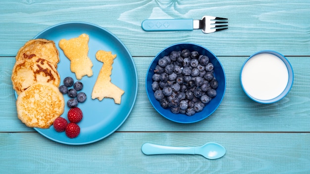 Foto gratuita vista superior de arándanos con comida para bebés y cubiertos