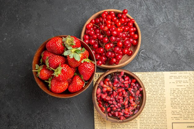 Vista superior de arándanos rojos frescos con otras frutas sobre fondo oscuro