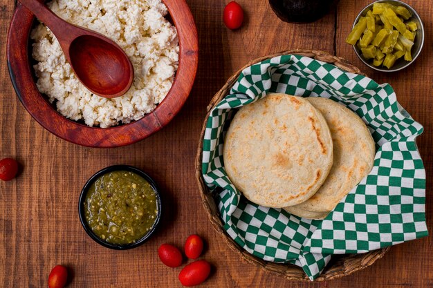 Vista superior de arepas en canasta con salsa y tomates cherry