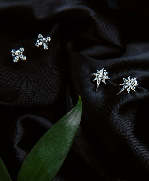 Vista superior de aretes de plata esterlina con diamantes con tachuelas en la pared negra