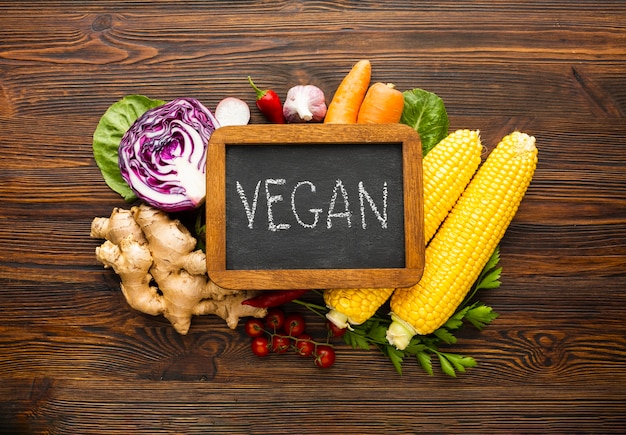 Foto gratuita vista superior arreglo vegetal con letras veganas en pizarra