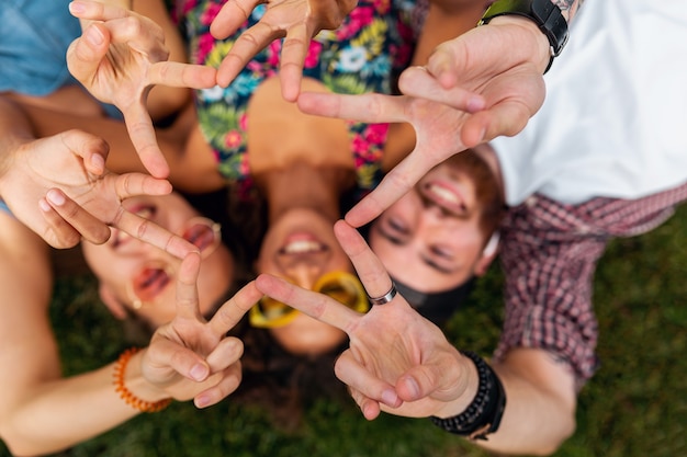 Vista superior desde arriba en la colorida y elegante compañía joven feliz de amigos tumbados en la hierba en el parque, hombres y mujeres divirtiéndose juntos