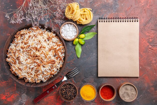 Vista superior de arroz cocido con condimentos en la superficie oscura comida oscura foto plato comida