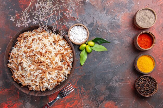 Vista superior de arroz cocido con condimentos en una superficie oscura plato fotográfico oscuro