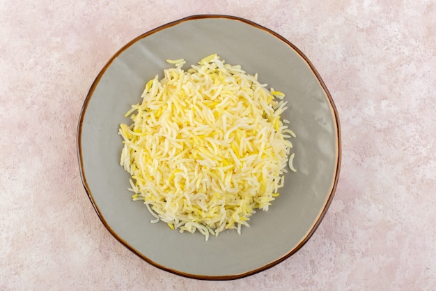 Una vista superior de arroz cocido dentro de la placa en el escritorio rosa comida comida cocina sabor