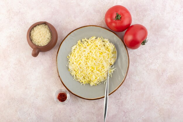 Una vista superior de arroz cocido dentro de un plato redondo con tomates rojos frescos en el escritorio rosa comida comida arroz vegetal