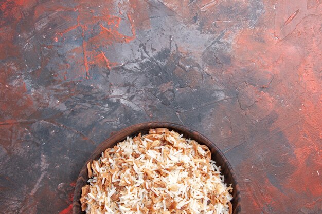 Vista superior de arroz cocido con rodajas de masa en plato de superficie oscura pasta de comida oscura