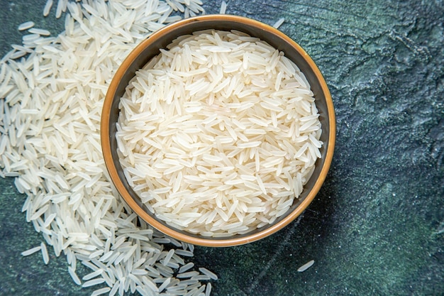 Vista superior del arroz crudo dentro de la placa en el escritorio oscuro