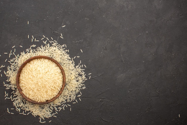 Foto gratuita vista superior del arroz crudo dentro de la placa sobre superficie gris oscuro
