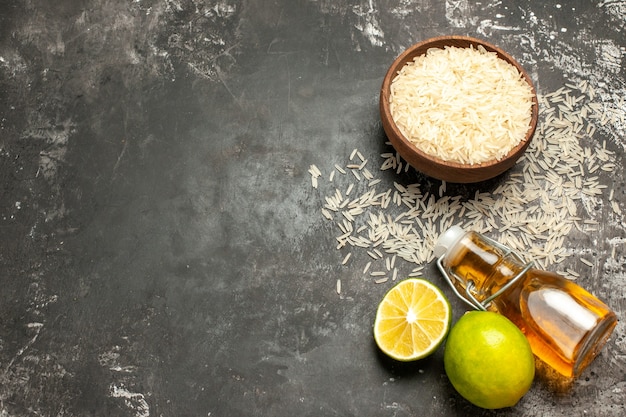 Vista superior de arroz crudo con limones y aceite en frutas de alimentos crudos de superficie oscura