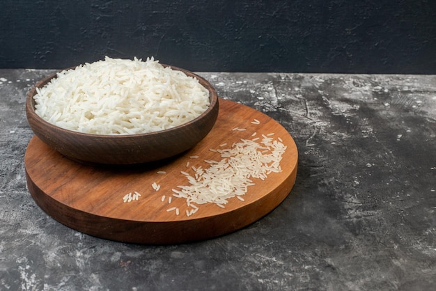 Vista superior del arroz largo perfecto en un tazón marrón y en una tabla de madera sobre fondo gris