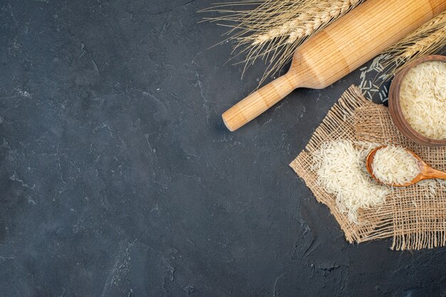 Vista superior de arroz en un tazón y un rodillo de cuchara de madera en la mesa con espacio libre