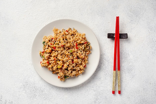 Vista superior de arroz con verduras en plato y palillos