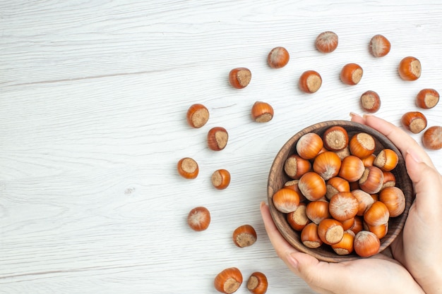 Vista superior de avellanas crudas frescas en blanco escritorio tuerca película planta alimentos nueces bocadillo