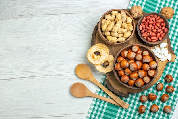 Vista superior de avellanas crudas frescas con cacahuetes en nuez de mesa blanca comida vegetal snack película nuez