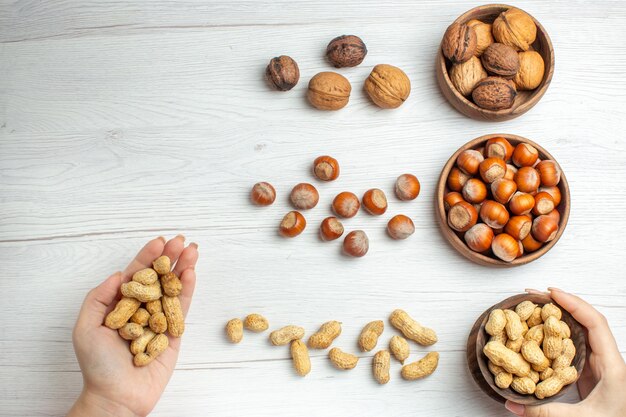 Vista superior de avellanas frescas con maní y nueces en mesa blanca