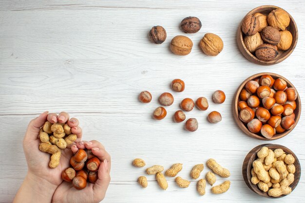 Vista superior de avellanas frescas con maní y nueces en mesa blanca